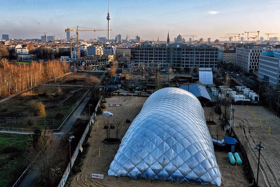 Paranet Nutzungskonzept Beachvolleyball 4 Luftaufnahme einer silbrigen Traglufthalle mit Blick auf die Stadt und den Berliner Fernsehturm.