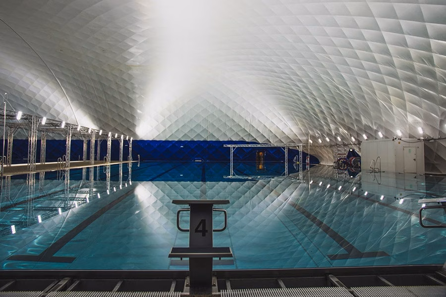 Paranet Nutzungskonzept Schwimmen 1 Blick von Startblock 4 über ein langes, ruhiges Schwimmbecken unter einer Traglufthalle.