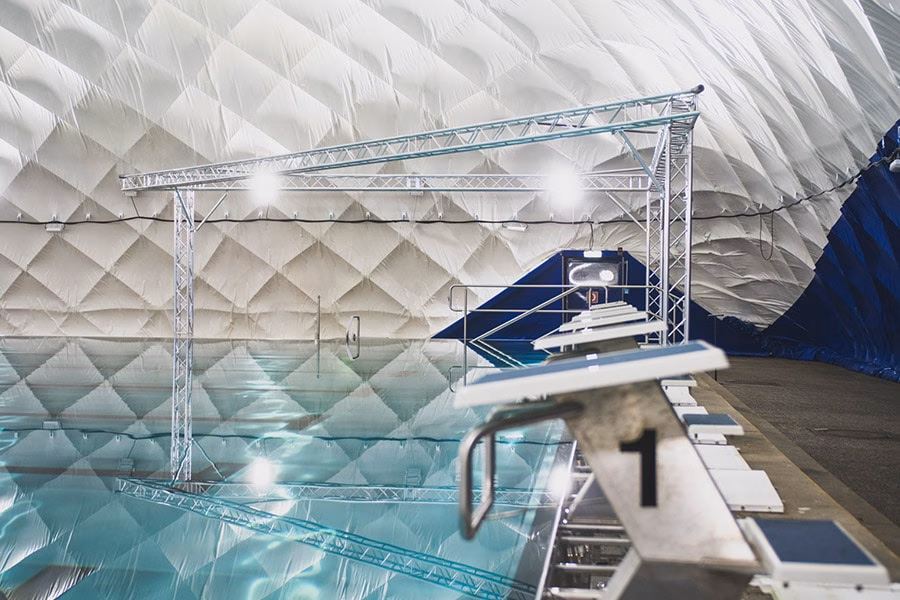 Paranet Nutzungskonzept Schwimmen 4 Startblock mit der Nummer 1 am Beckenrand eines Hallenbads unter einer Traglufthalle.