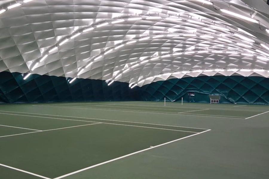 Paranet Nutzungskonzept Tennis Traglufthalle Grüne Tennis-Plätze im Innenraum einer weiträumigen Traglufthalle mit heller Deckenbeleuchtung.