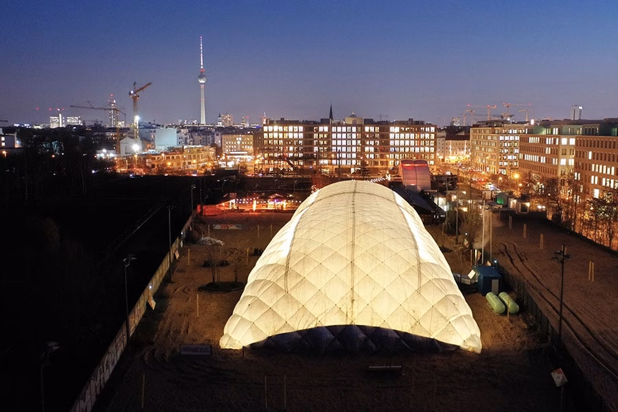 Paranet Traglufthalle Impression 2 Beleuchtete PARANET Traglufthalle bei Nacht mit Blick auf die Berliner Skyline und den Fernsehturm im Hintergrund.